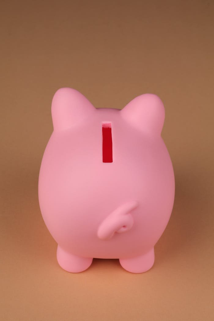 Pink piggy bank standing on a neutral brown surface, captured in a minimalist style.