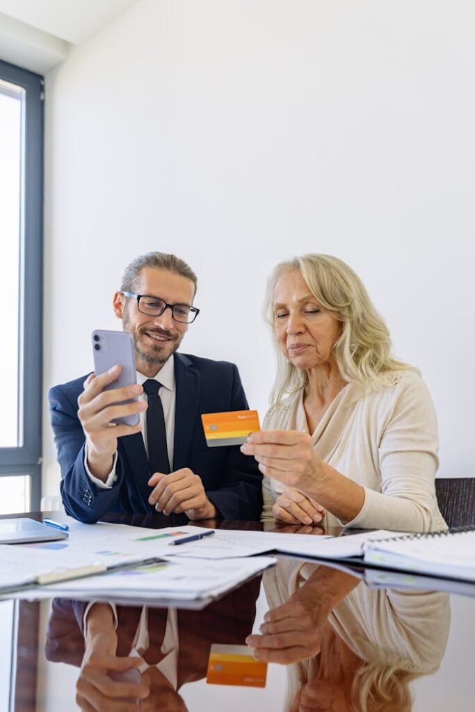 pexels-photo-5816301 Senior woman and businessman discussing finance using smartphone and credit card in office.